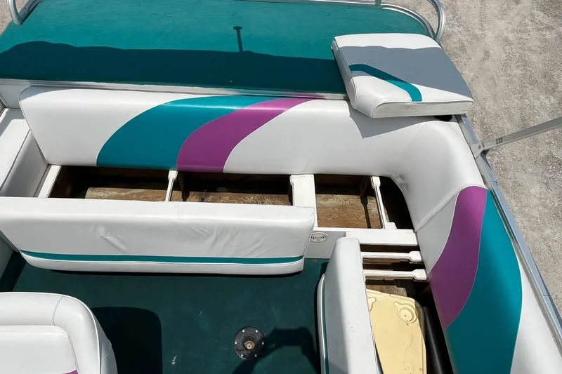 Slide: The Image of 1998 Sundancer Pontoons 240 interior with colorful seating and open storage compartments. - 11