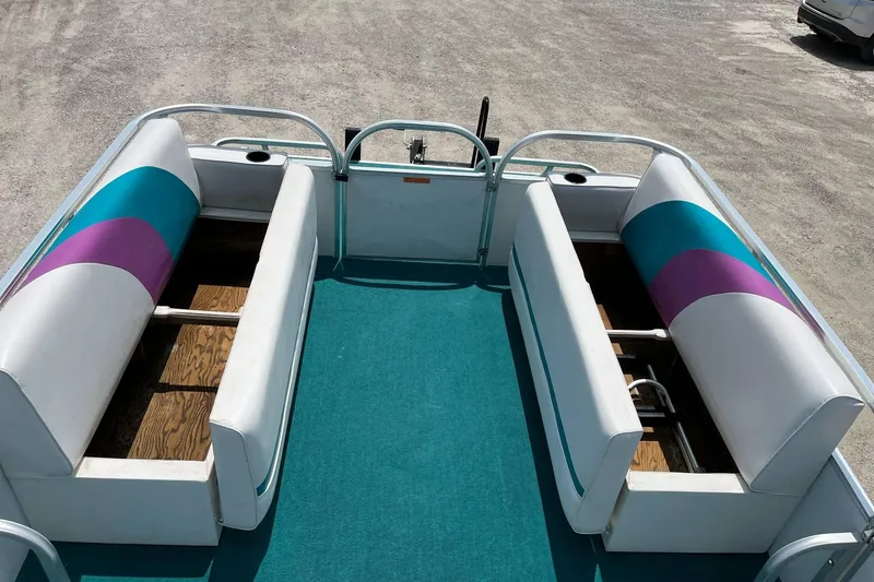Slide: The Image of 1998 Sundancer Pontoons 240 interior with teal and purple seating, open storage compartments. - 3
