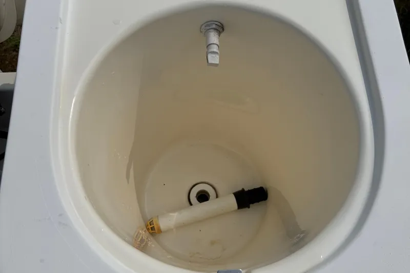 Slide: The Image of Livewell interior of 2001 Mako 221 Center Console boat, featuring a drain and hose. - 10