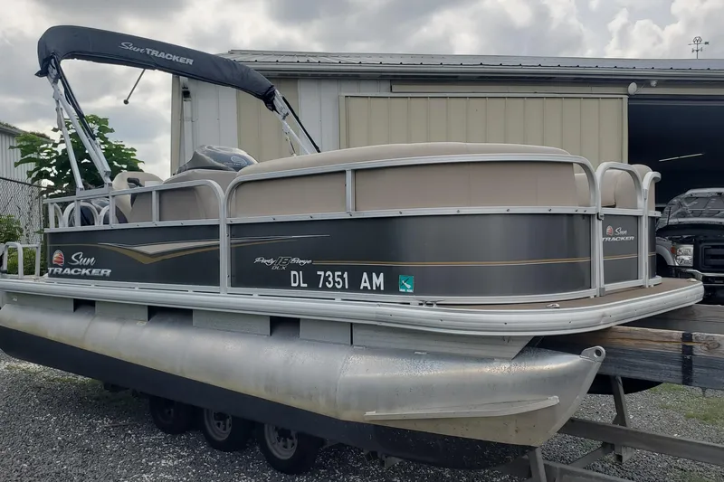 The Image of 2020 SUNTRACKER Party Barge 180 DLX pontoon boat on trailer, parked outdoors. - 1