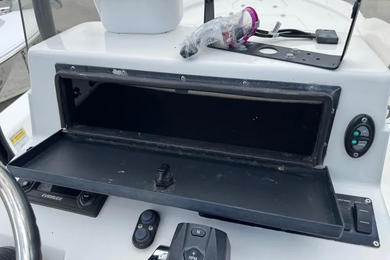 Slide: The Image of Open storage compartment on 2015 BlackJack 224 Bay boat dashboard with controls and items. - 11
