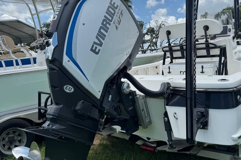 Slide: The Image of 2015 BlackJack 224 Bay boat with Evinrude outboard motor, parked on grass. - 2