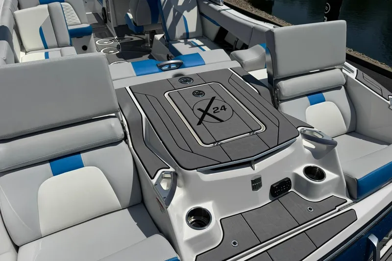 Slide: The Image of 2020 MasterCraft X24 boat interior with gray and blue seating, cup holders, and deck. - 15