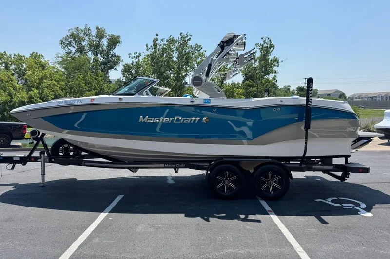 Slide: The Image of 2020 MasterCraft X24 boat on trailer, blue and white design, parked outdoors. - 6