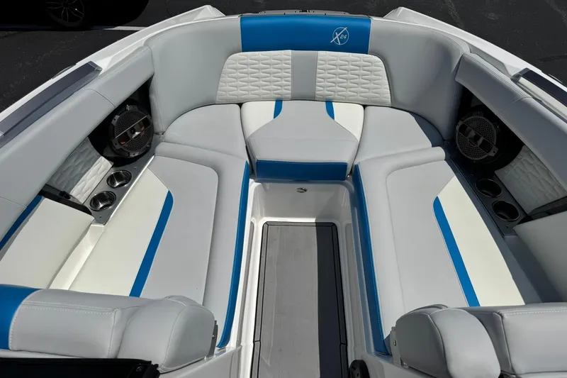 Slide: The Image of 2020 MasterCraft X24 boat interior with blue and white seating, cup holders, and speakers. - 7