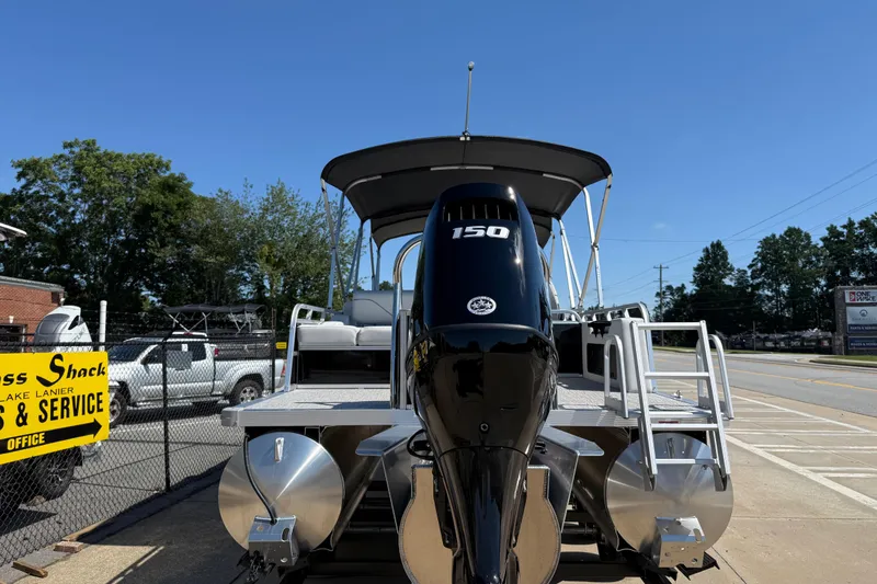 Slide: The Image of 2026 Avalon Venture 85 Versatile rear Bench pontoon boat with 150 HP engine, parked outdoors. - 5