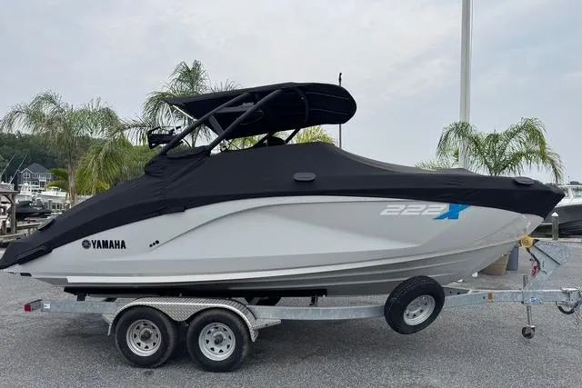 Slide: The Image of 2023 Yamaha Boats 222XD on trailer, covered, with palm trees in background. - 4