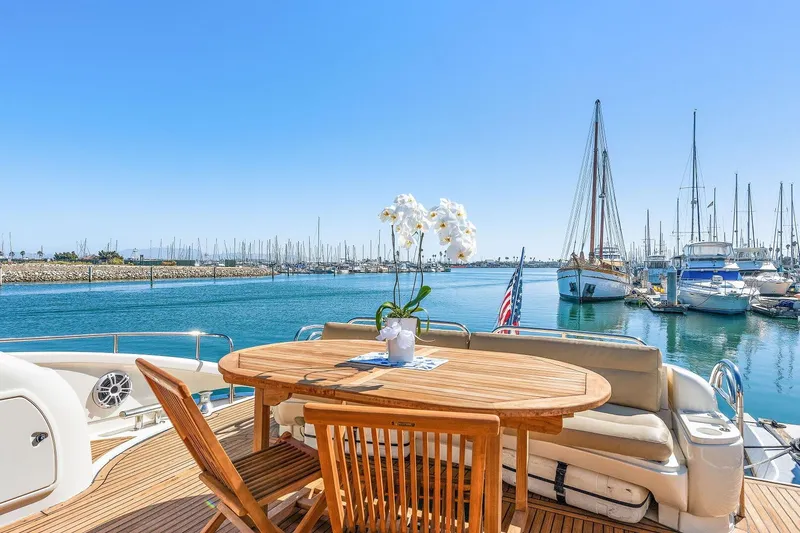 Slide: The Image of Sunseeker Predator 80 yacht deck with wooden table, marina view, and clear blue sky. - 21