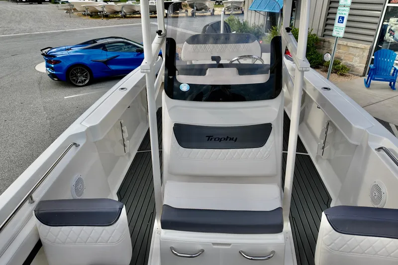 Slide: The Image of 2024 Bayliner TROPHY 22 CX boat interior with seating, parked blue sports car in background. - 10