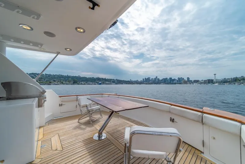 Slide: The Image of 2005 Ocean Alexander 64 Motoryacht deck with city skyline view, featuring seating and table. - 47