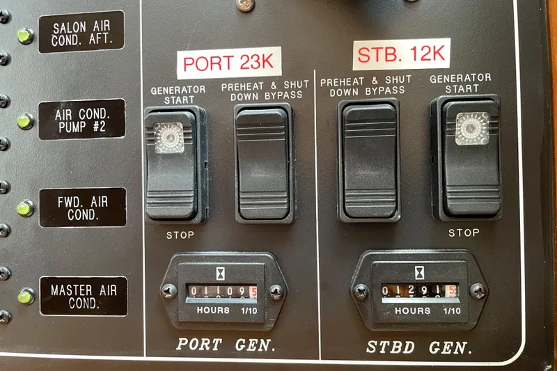 Slide: The Image of Control panel of a 2005 Ocean Alexander 64 yacht, showing generator switches and hour meters. - 61