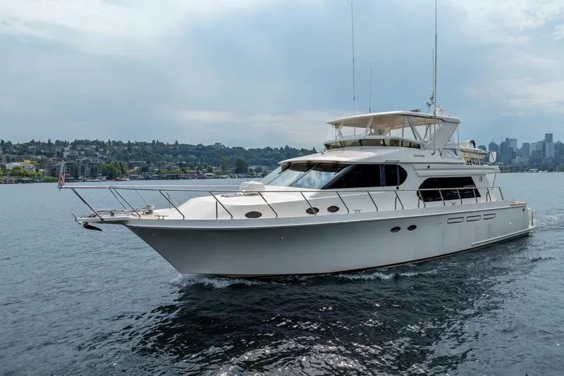 Slide: The Image of 2005 Ocean Alexander 64 Motoryacht cruising on a calm waterway with cityscape background. - 9