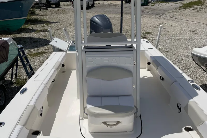Slide: The Image of 2015 Robalo 246 Cayman boat interior with seating and storage, parked on gravel. - 10