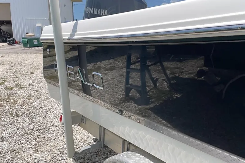 Slide: The Image of 2015 Robalo 246 Cayman boat side view with Yamaha branding, parked on gravel. - 12