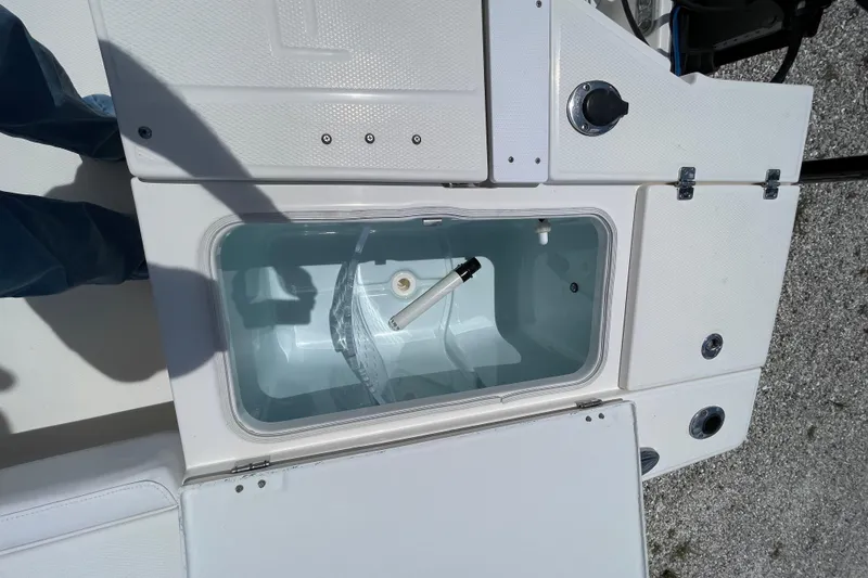Slide: The Image of 2015 Robalo 246 Cayman boat storage compartment with open lid, showing interior details. - 16