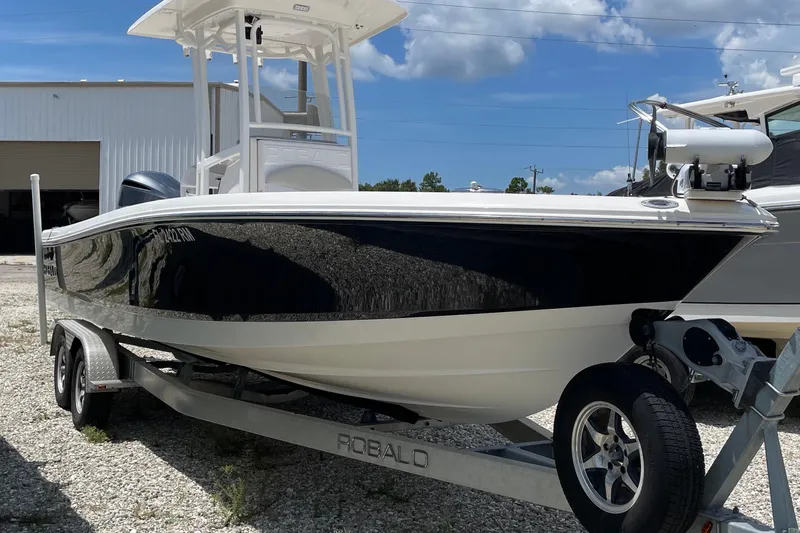 Slide: The Image of 2015 Robalo 246 Cayman boat on trailer, parked outdoors under blue sky. - 17