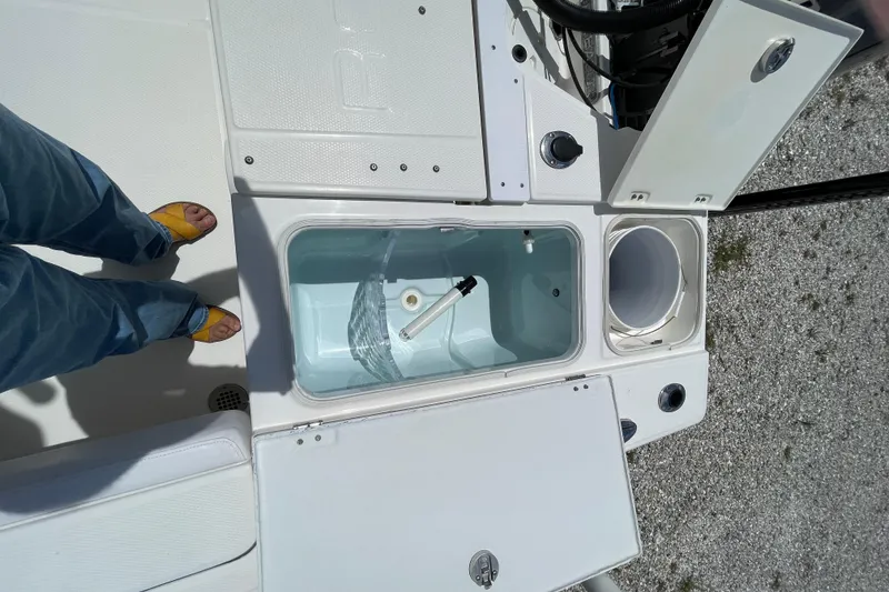 Slide: The Image of 2015 Robalo 246 Cayman boat deck with open storage compartments and person standing. - 6