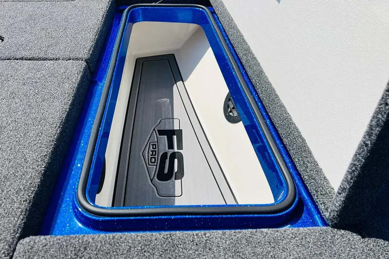 Slide: The Image of 2024 Ranger 620FS Pro boat storage compartment with FS Pro logo, blue trim, and gray carpet. - 28