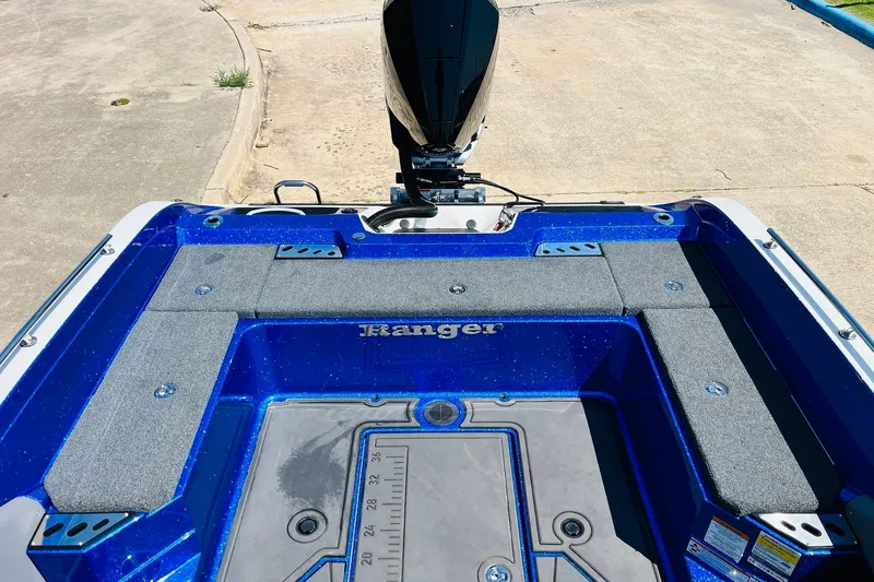 Slide: The Image of 2024 Ranger 620FS Pro boat deck with blue finish and motor, parked on concrete. - 56