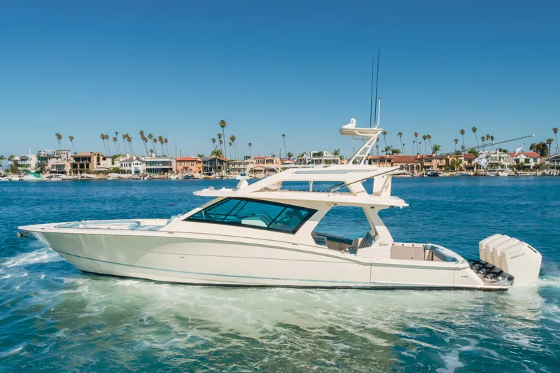 Slide: The Image of 2023 Scout 530 LXF luxury yacht cruising near coastal homes and palm trees. - 1