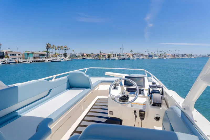 Slide: The Image of 2023 Scout 530 LXF boat interior with steering wheel, blue seating, and waterfront view. - 20