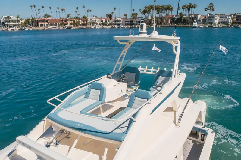 Slide: The Image of 2023 Scout 530 LXF luxury boat cruising near waterfront homes and palm trees. - 25