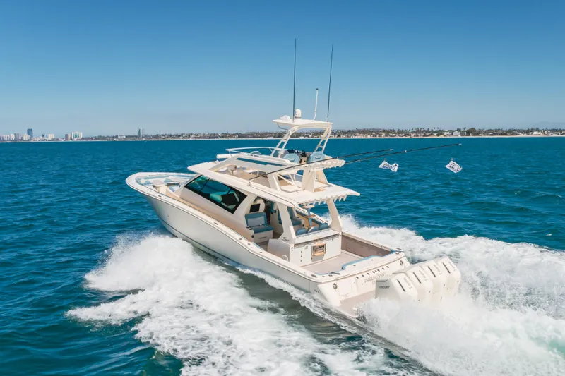 Slide: The Image of 2023 Scout 530 LXF luxury boat cruising on open water, city skyline in background. - 26