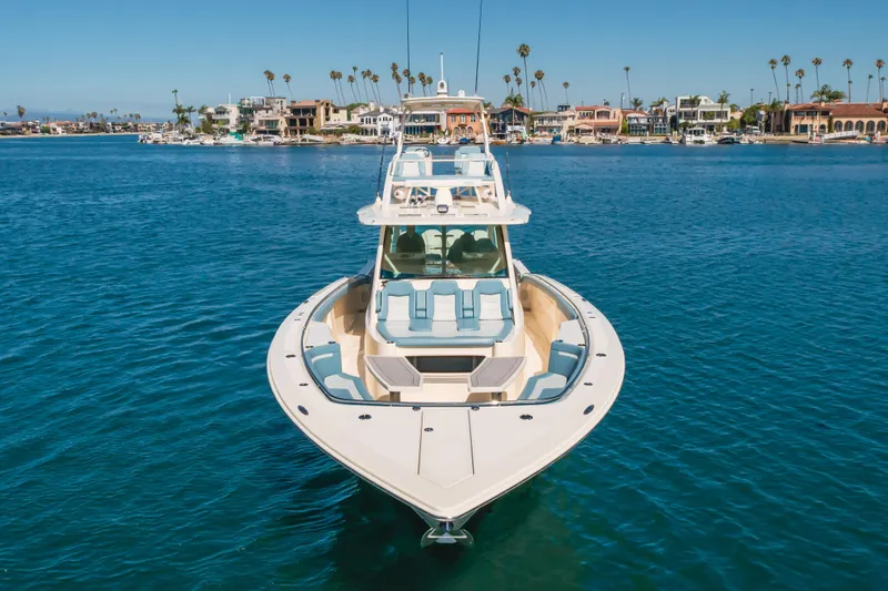 Slide: The Image of 2023 Scout 530 LXF luxury boat on calm water near coastal homes. - 28