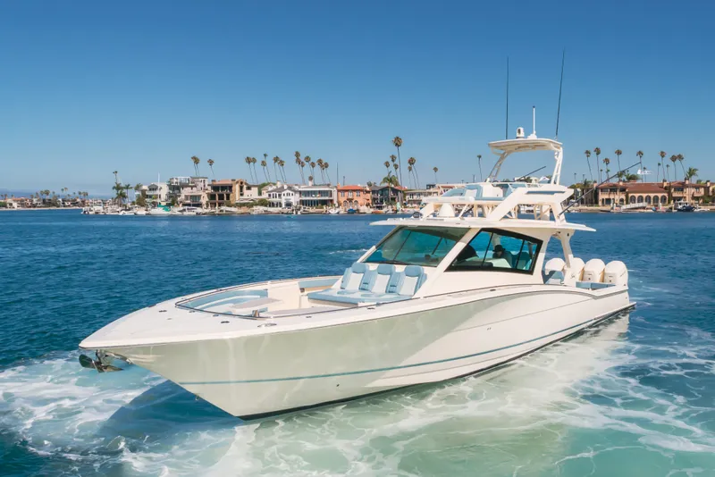 Slide: The Image of 2023 Scout 530 LXF luxury yacht cruising near coastal homes under clear blue skies. - 29