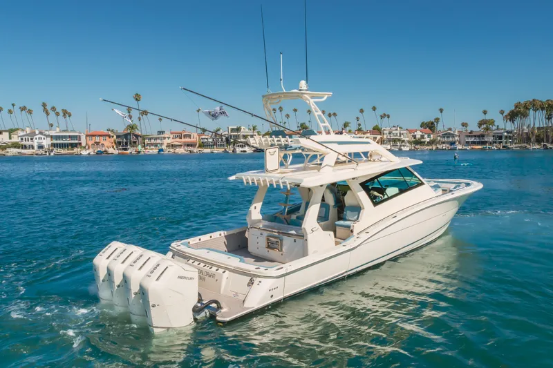 Slide: The Image of 2023 Scout 530 LXF luxury boat cruising near coastal homes and palm trees. - 30