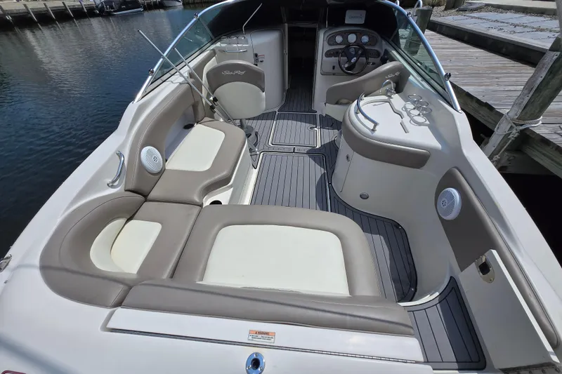 Slide: The Image of 2006 Sea Ray 270 Sundeck interior with seating and helm, docked by the water. - 2