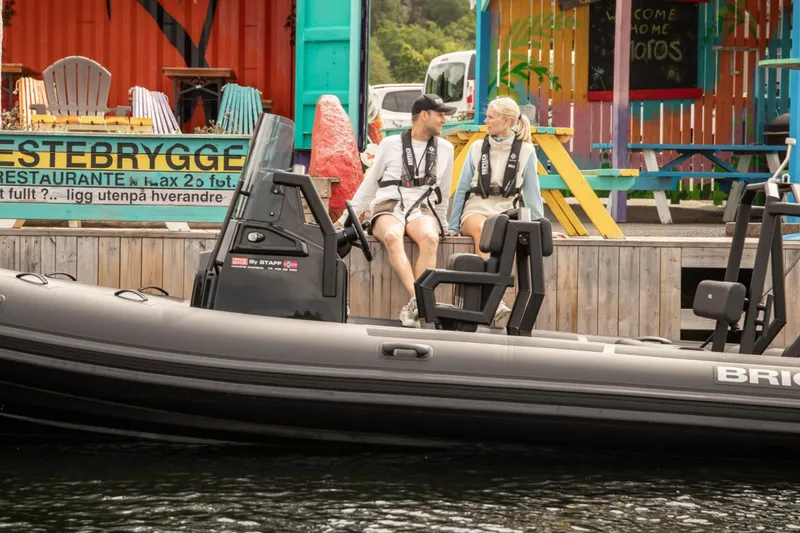 Slide: The Image of Couple sitting on a 2026 Brig Navigator 20 boat docked near colorful restaurant. - 4