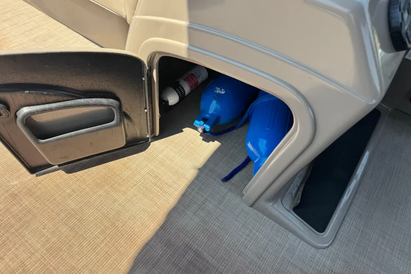 Slide: The Image of Storage compartment in a 2021 Sun Tracker SportFish 22 DLX, containing blue fenders and a fire extinguisher. - 27