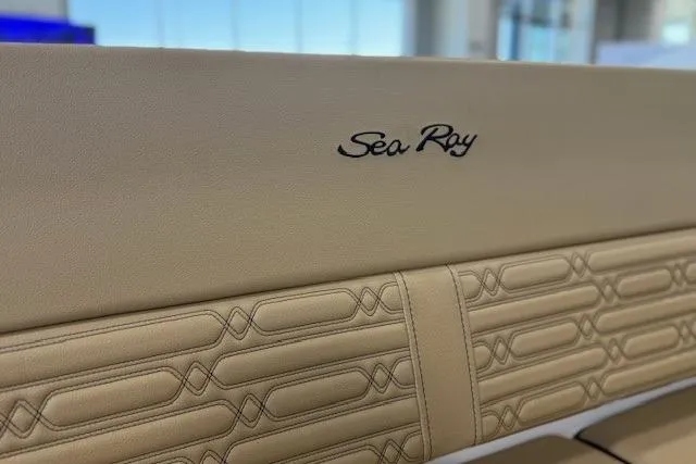 Slide: The Image of 2024 Sea Ray SPX 210 boat interior with beige leather seating and logo detail. - 13