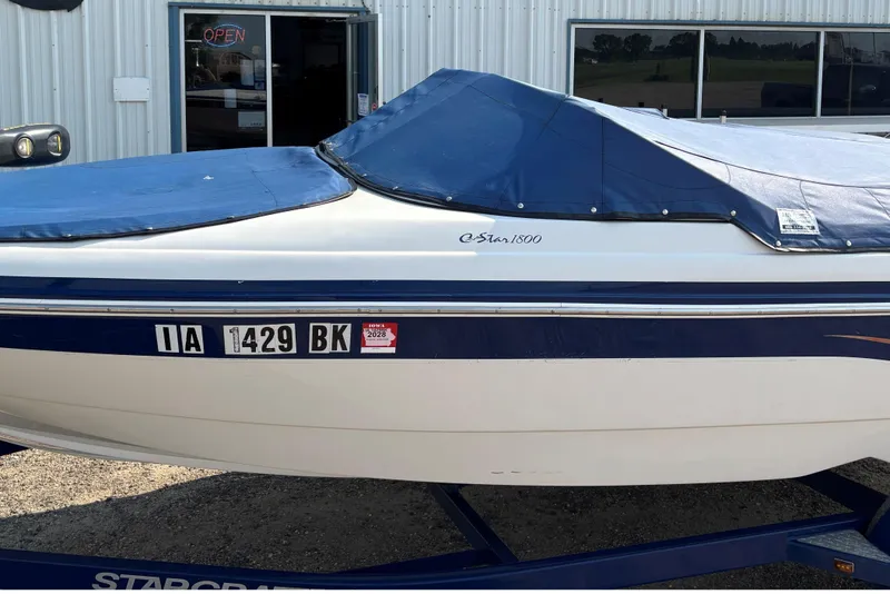 Slide: The Image of 2006 Starcraft C-Star 1800 I/O boat with blue cover, parked outside a building. - 18