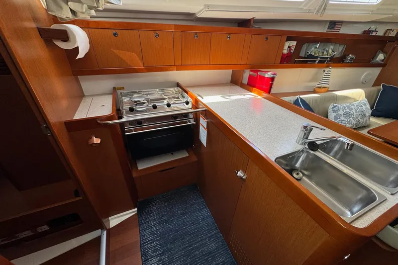 Slide: The Image of 2017 Beneteau Oceanis 37 yacht interior kitchen with stove, sink, and wooden cabinetry. - 24