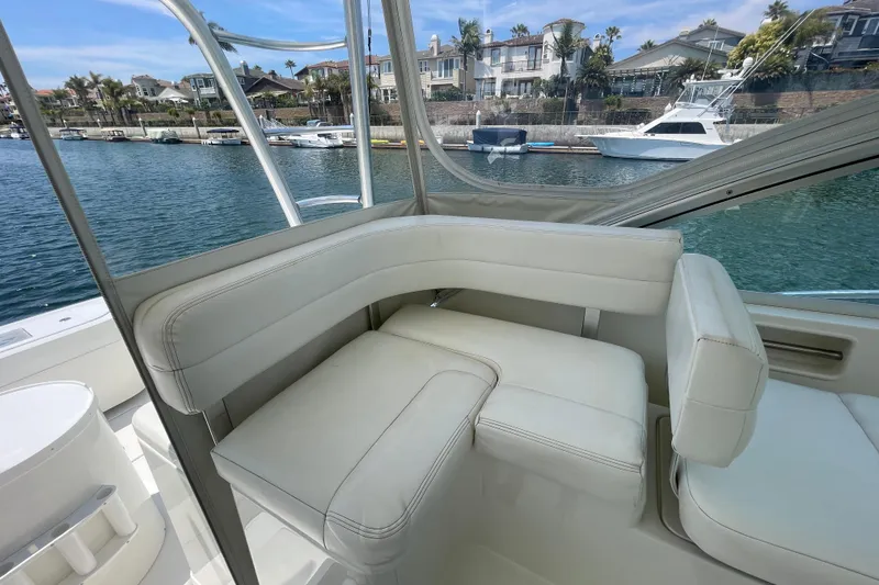 Slide: The Image of 2005 Rampage 33 Express boat interior with white seating, docked near waterfront homes. - 22