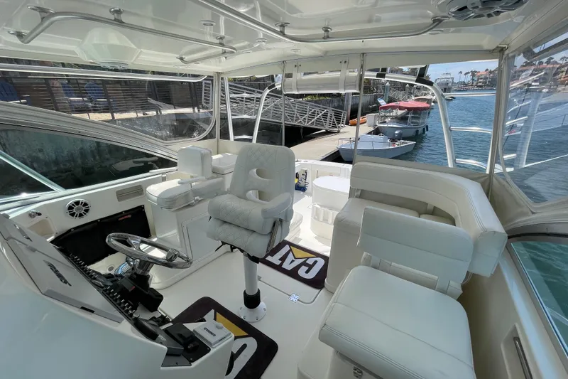 Slide: The Image of 2005 Rampage 33 Express boat interior with white seating and steering wheel, docked by the water. - 24