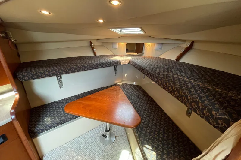 Slide: The Image of Interior cabin of 2005 Rampage 33 Express boat with cushioned seating and wooden table. - 38