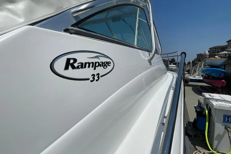 Slide: The Image of 2005 Rampage 33 Express boat docked, showcasing sleek design and logo. - 6