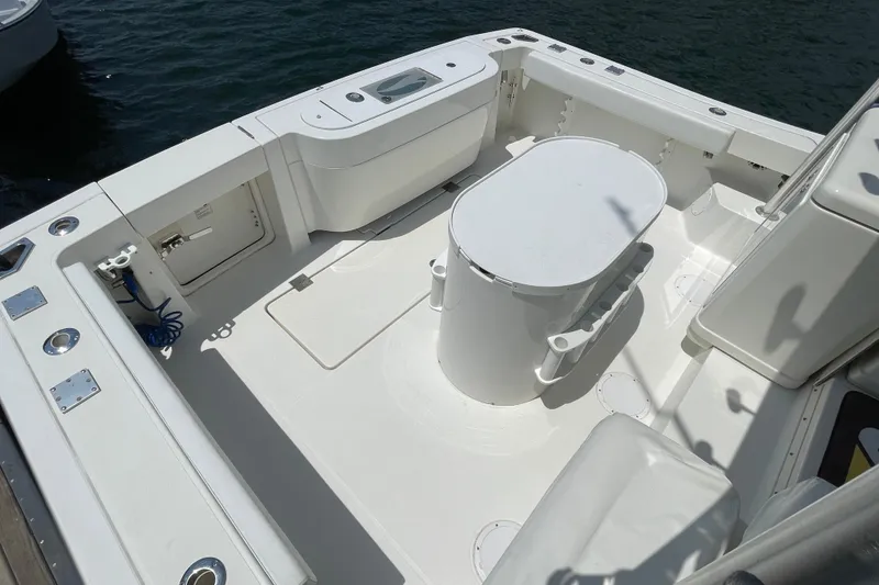 Slide: The Image of 2005 Rampage 33 Express boat deck with seating and storage, docked on calm water. - 7