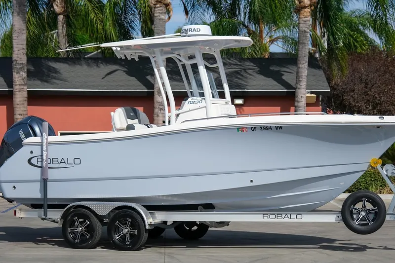 Slide: The Image of 2023 Robalo R230 Center Console boat on trailer, parked outdoors. - 1