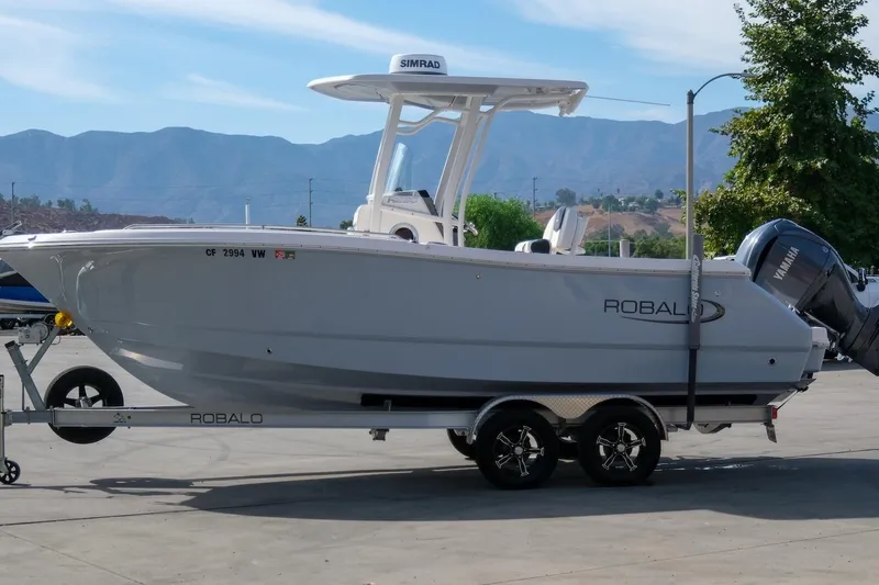 Slide: The Image of 2023 Robalo R230 Center Console boat on trailer with mountainous backdrop. - 2