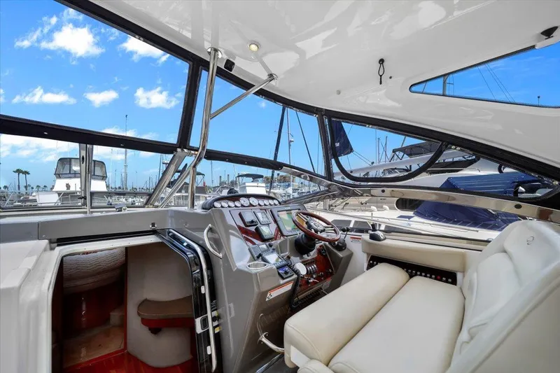 Slide: The Image of 2010 Regal Commodore 4460 yacht interior with helm, leather seating, and marina view. - 16