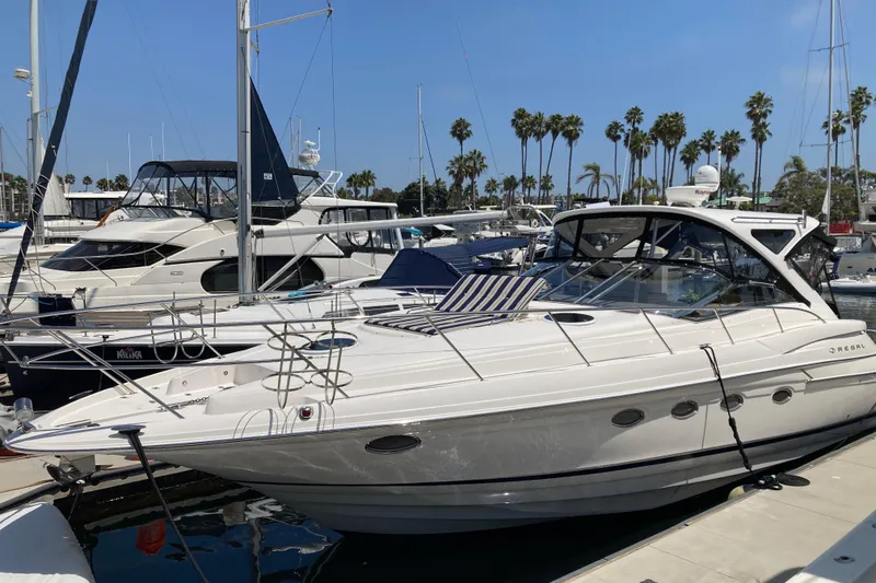 Slide: The Image of 2010 Regal 4460 Monterrey yacht docked in a marina with palm trees in the background. - 2