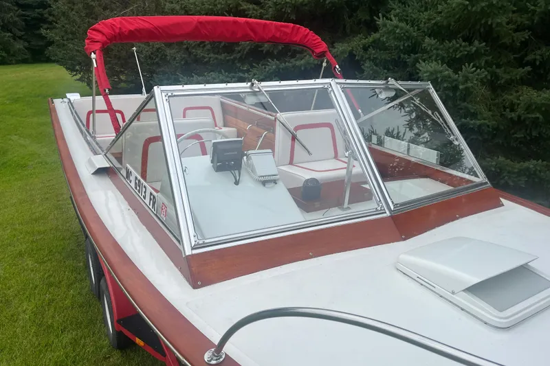 Slide: The Image of 1964 Chris-Craft Sea Skiff boat with red accents and windshield, parked on grass. - 1