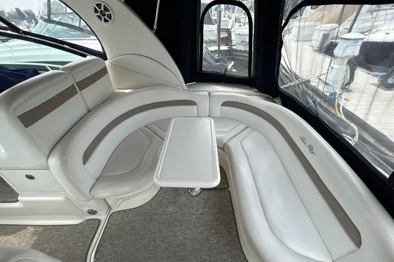 Slide: The Image of 2005 Sea Ray 320 Sundancer interior with curved seating and table, docked at marina. - 12