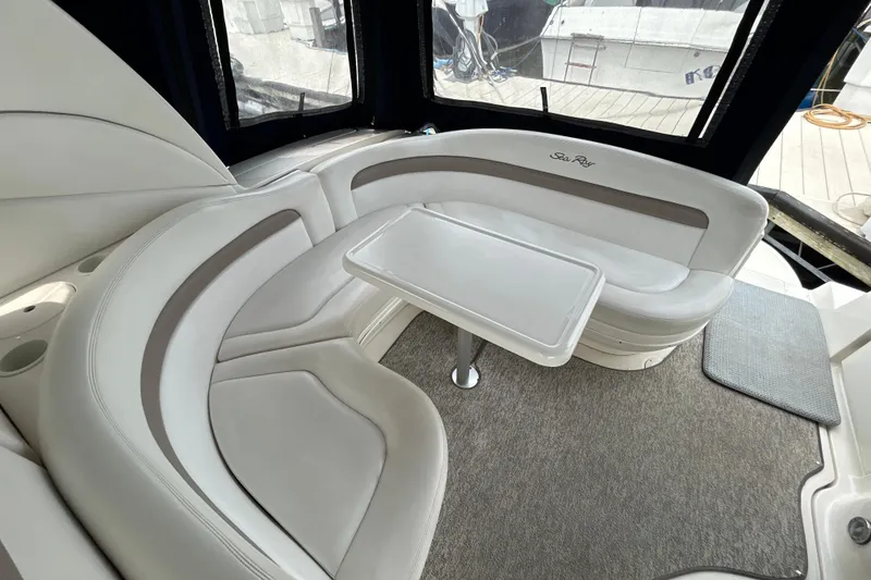 Slide: The Image of 2005 Sea Ray 320 Sundancer interior with curved seating and table, featuring elegant design. - 13