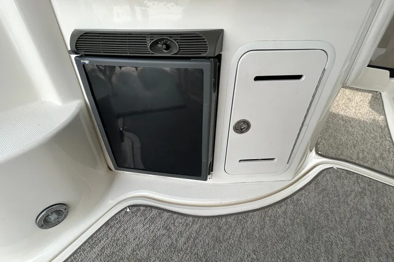 Slide: The Image of 2005 Sea Ray 320 Sundancer interior with mini fridge and storage compartment. - 20