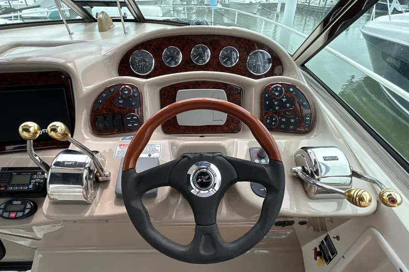 Slide: The Image of 2005 Sea Ray 320 Sundancer helm with wood-accented steering wheel and control panel. - 29